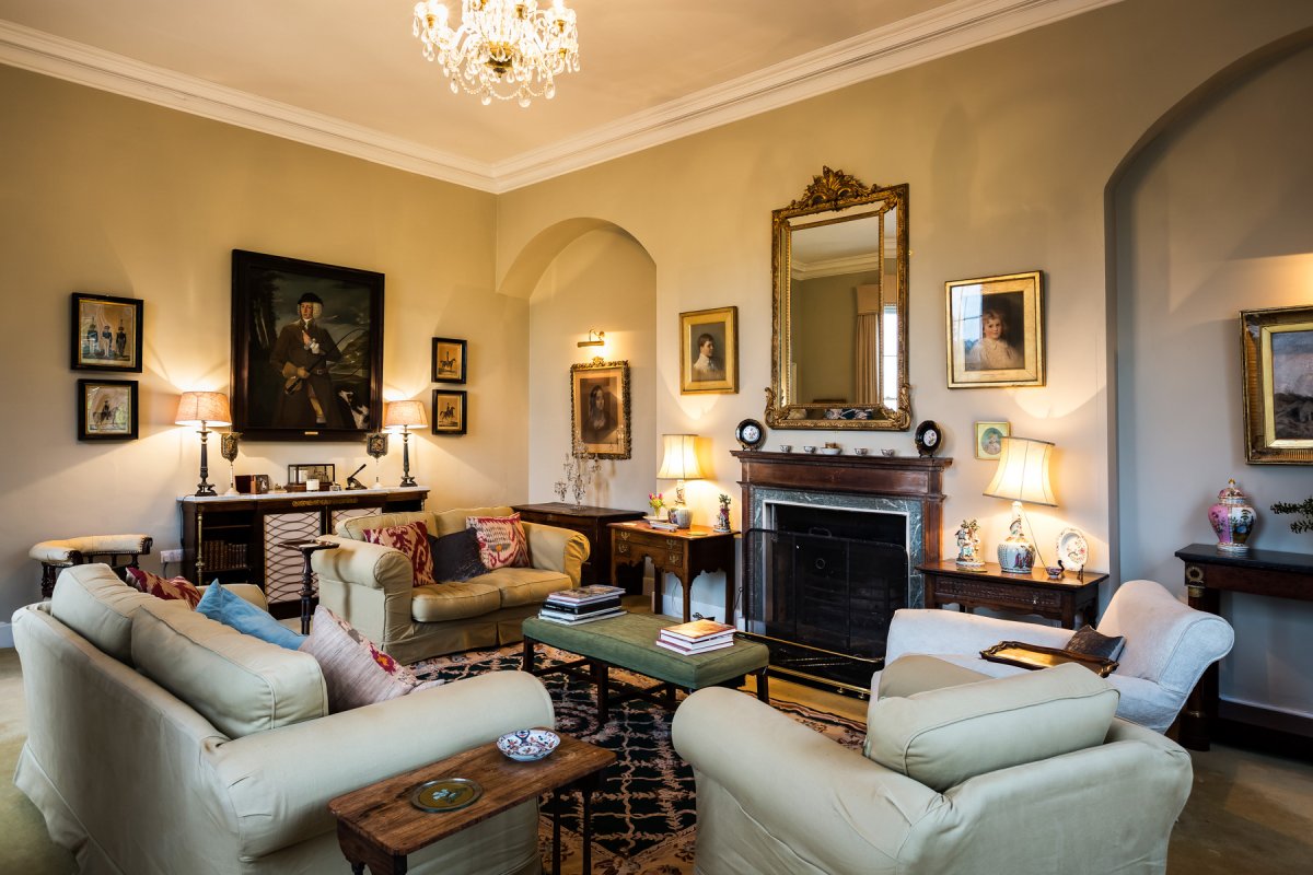 Formal drawing room with open fire and antique furniture and paintings