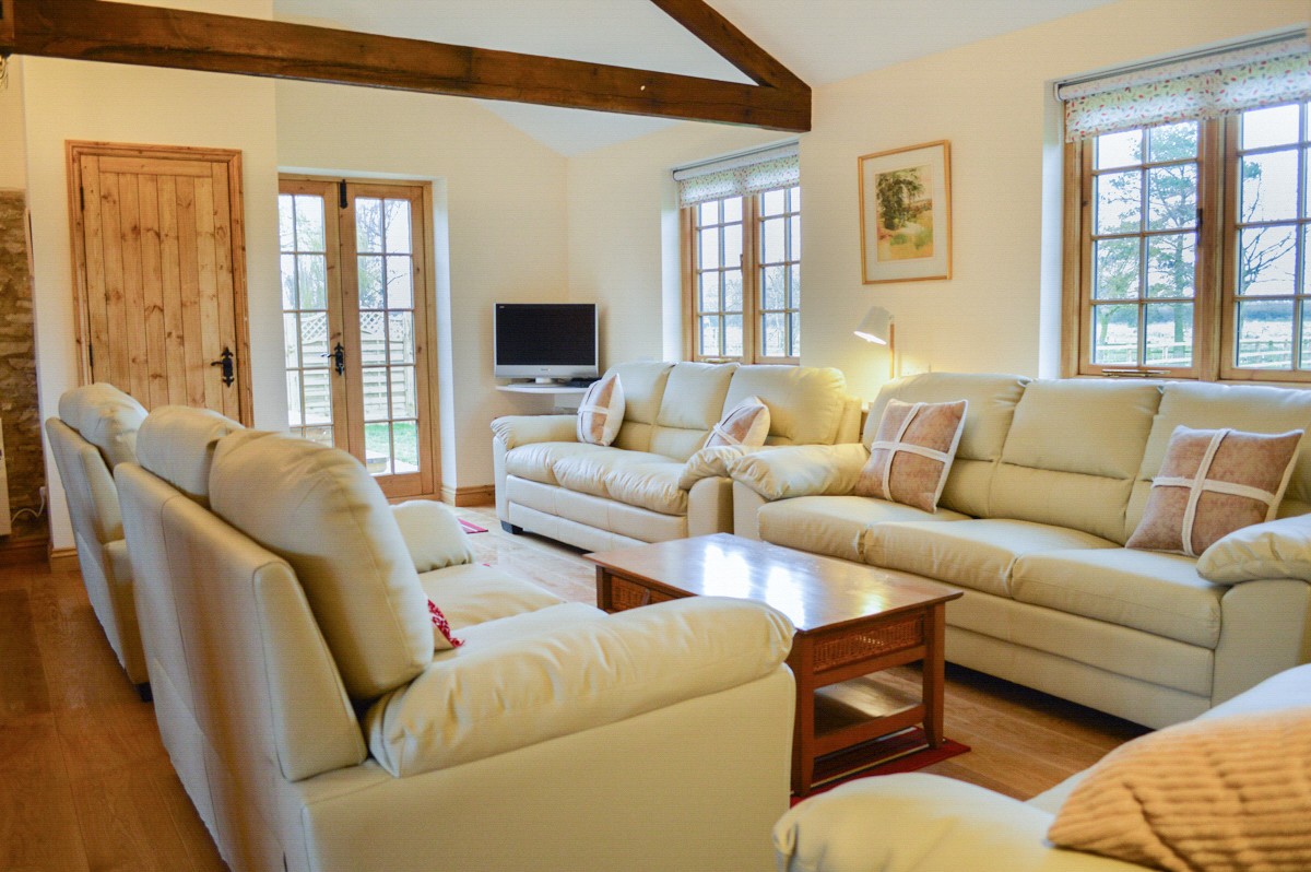 Sitting room with numerous sofas and chairs, and exposed timbers and beams over.